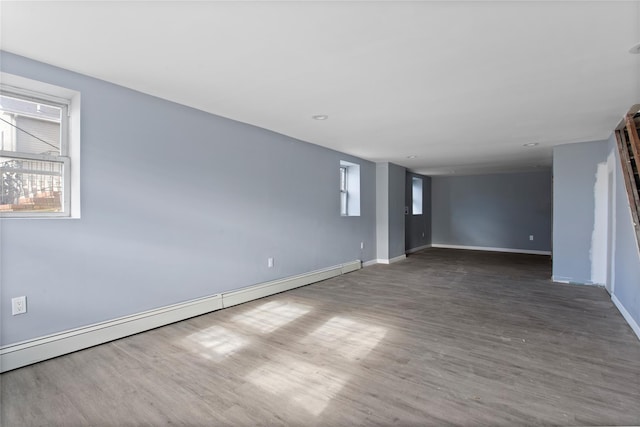 empty room with a baseboard radiator, wood finished floors, and baseboards