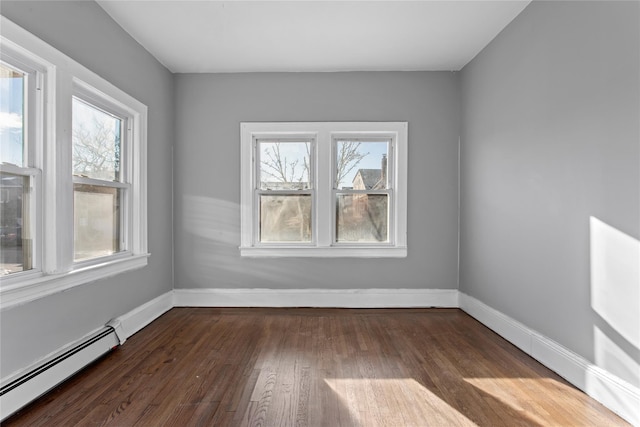 spare room with baseboards, baseboard heating, and dark wood-type flooring