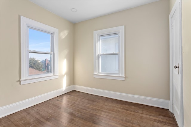 unfurnished room featuring baseboards and dark wood finished floors