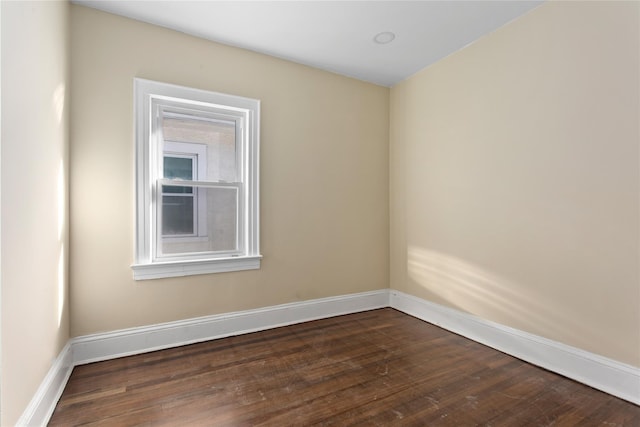 spare room with dark wood-style flooring and baseboards