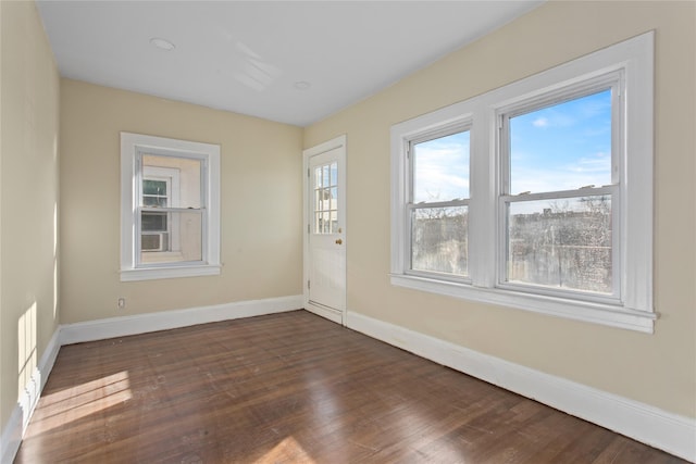 spare room with baseboards and dark wood finished floors