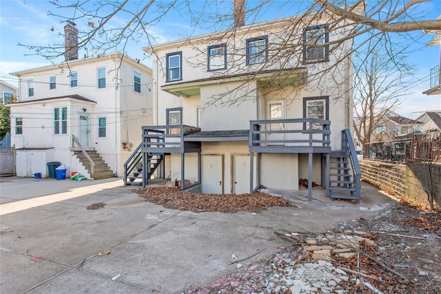 rear view of property featuring stairs, fence, a wooden deck, and stucco siding