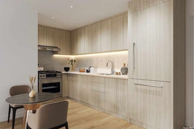 kitchen featuring tasteful backsplash, sink, stainless steel gas range oven, light brown cabinets, and light hardwood / wood-style flooring