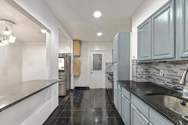 kitchen featuring pendant lighting, appliances with stainless steel finishes, dark tile patterned floors, decorative backsplash, and sink