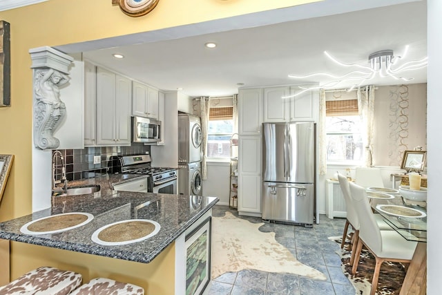 kitchen featuring kitchen peninsula, appliances with stainless steel finishes, and stacked washer and dryer