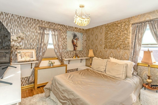 bedroom with radiator, a chandelier, and light hardwood / wood-style flooring