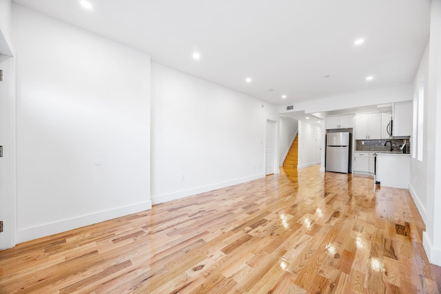 unfurnished living room featuring sink and light hardwood / wood-style flooring