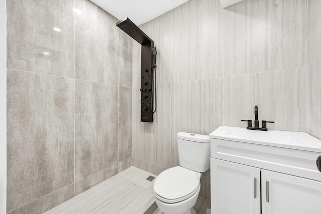 bathroom with toilet, a shower, vanity, and tile walls