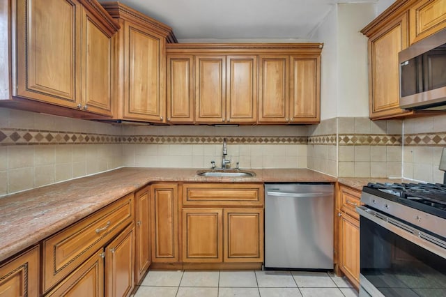 kitchen featuring stainless steel appliances, brown cabinetry, a sink, and light tile patterned floors