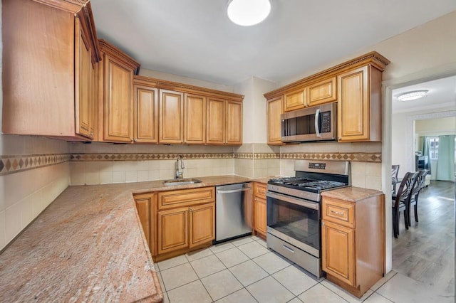 kitchen featuring a sink, light countertops, appliances with stainless steel finishes, backsplash, and brown cabinetry