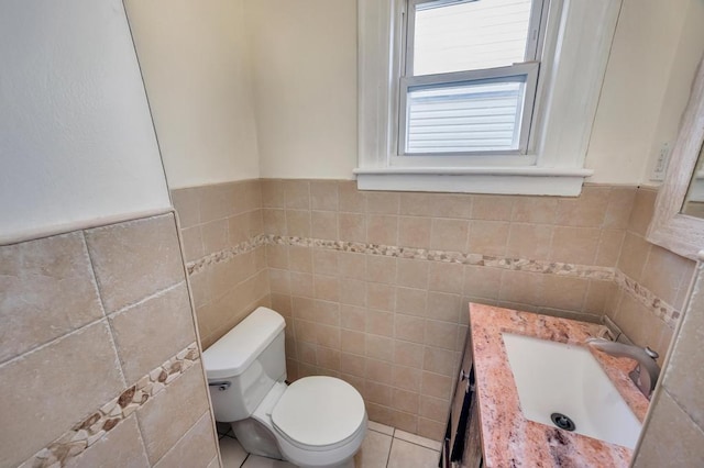 half bathroom featuring toilet, tile patterned floors, vanity, and tile walls