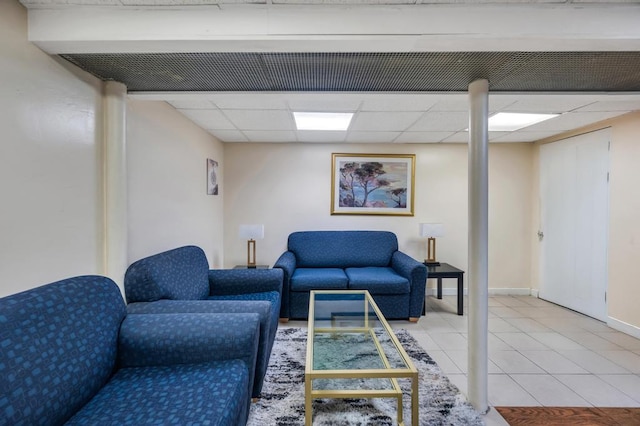 living room with baseboards, a drop ceiling, and tile patterned floors