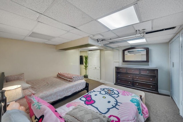 bedroom with carpet, a drop ceiling, and baseboards