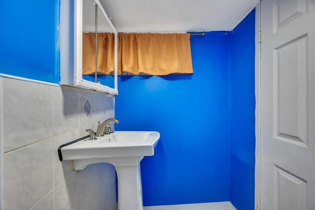 bathroom with a sink and tile walls