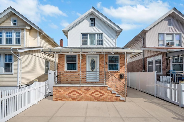 view of front facade featuring a fenced front yard, a porch, cooling unit, and brick siding