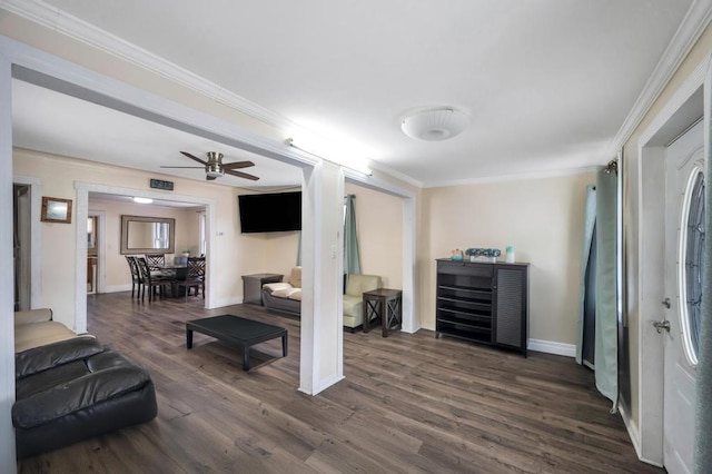 living room with dark wood-type flooring, a ceiling fan, visible vents, baseboards, and ornamental molding