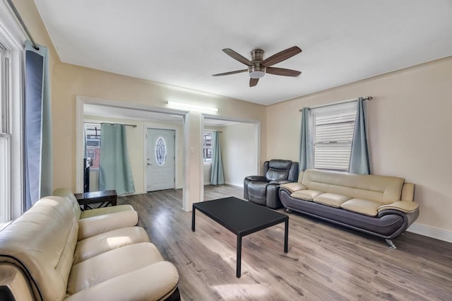 living room with a ceiling fan, a wealth of natural light, baseboards, and wood finished floors