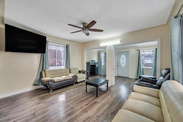 living area with ceiling fan, baseboards, wood finished floors, and a healthy amount of sunlight