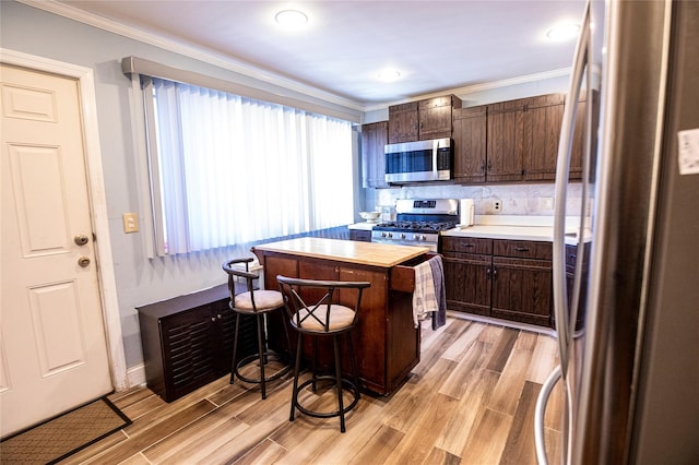 kitchen with a center island, light wood-type flooring, dark brown cabinetry, and appliances with stainless steel finishes