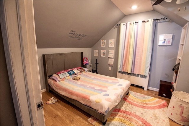 bedroom with ceiling fan, lofted ceiling, and light wood-type flooring