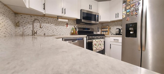 kitchen featuring stainless steel appliances, white cabinetry, and tasteful backsplash