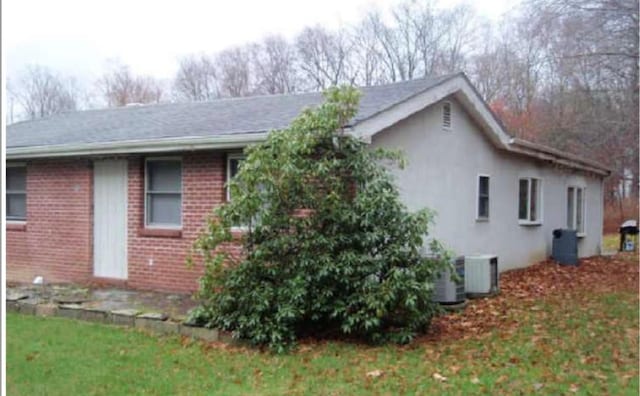 view of side of home with a yard and central air condition unit