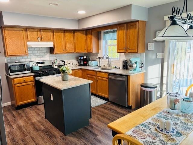 kitchen with dark hardwood / wood-style flooring, stainless steel appliances, sink, decorative light fixtures, and a center island