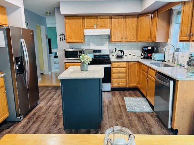 kitchen featuring sink, dark hardwood / wood-style floors, decorative backsplash, a kitchen island, and stainless steel appliances