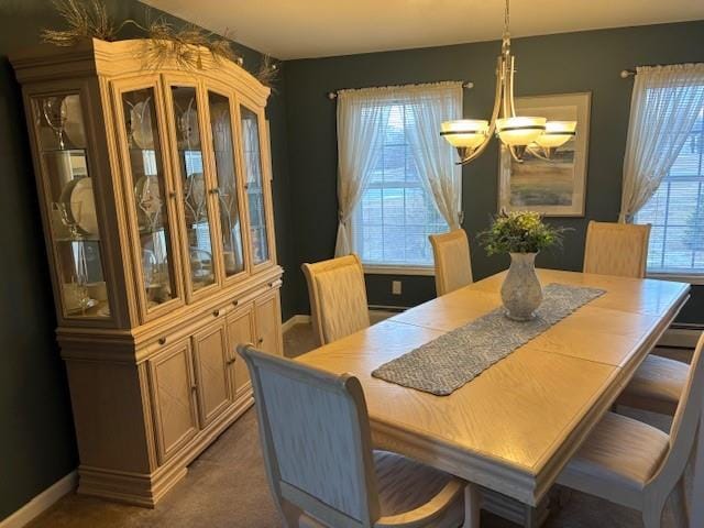 carpeted dining space featuring plenty of natural light and a chandelier