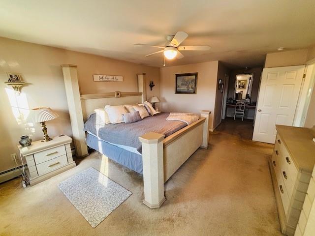 carpeted bedroom featuring ceiling fan and a baseboard heating unit