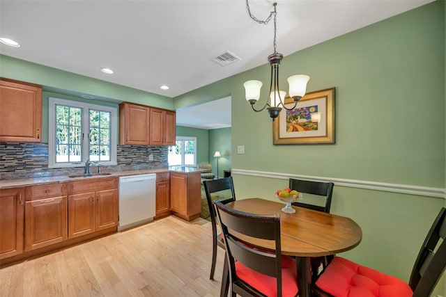 kitchen featuring dishwasher, sink, hanging light fixtures, tasteful backsplash, and a chandelier