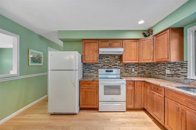 kitchen featuring white appliances, sink, light hardwood / wood-style flooring, decorative backsplash, and light stone counters