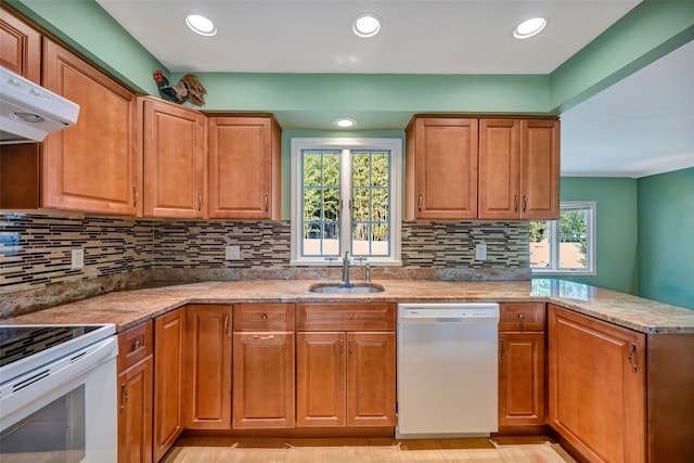 kitchen with decorative backsplash, white appliances, light stone counters, and sink