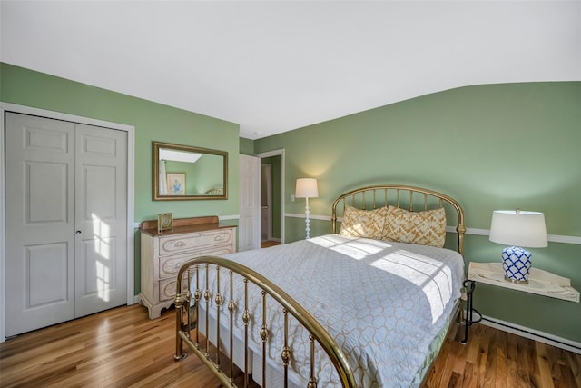 bedroom with lofted ceiling, wood-type flooring, and a closet