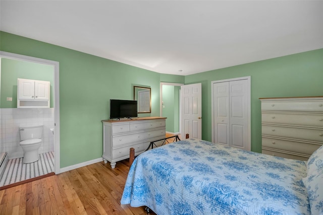 bedroom with ensuite bath, a closet, and light hardwood / wood-style flooring