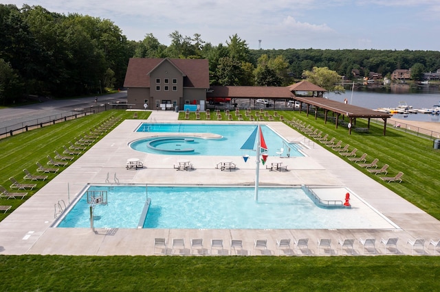 view of swimming pool featuring a yard, a water view, and a patio area