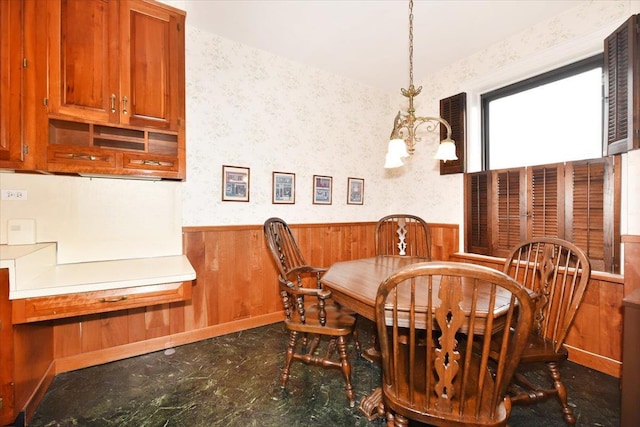 dining area with wooden walls and a notable chandelier