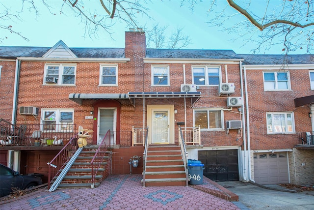 view of front of home featuring a garage and a wall mounted AC