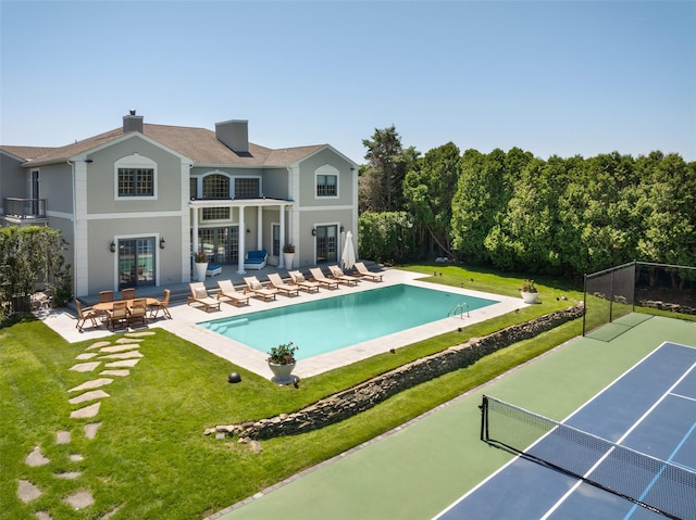 back of property featuring a yard, tennis court, and a patio area