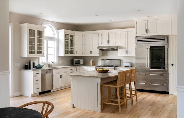 kitchen featuring white cabinetry, sink, a center island, stainless steel appliances, and light stone countertops