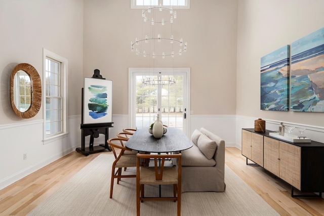 dining room with an inviting chandelier, light hardwood / wood-style flooring, and a high ceiling