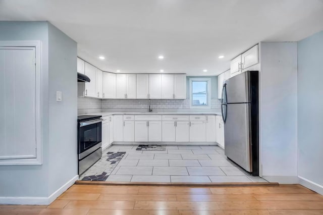 kitchen featuring a sink, under cabinet range hood, white cabinetry, appliances with stainless steel finishes, and decorative backsplash