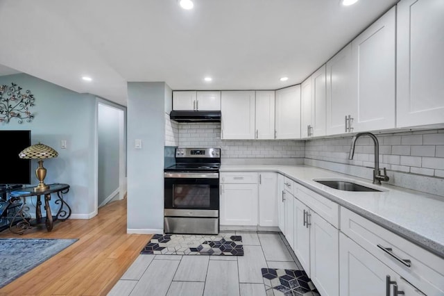 kitchen featuring under cabinet range hood, white cabinets, electric stove, and a sink