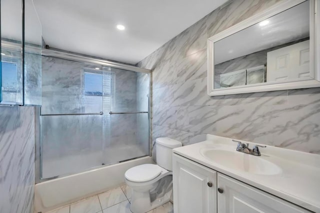 full bathroom featuring vanity, tile walls, toilet, and combined bath / shower with glass door