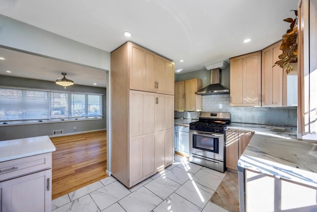 kitchen with tasteful backsplash, marble finish floor, gas range, and wall chimney exhaust hood