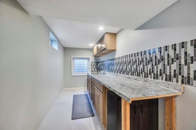 kitchen featuring a sink, wine cooler, light countertops, light tile patterned floors, and decorative backsplash