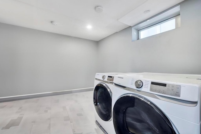 clothes washing area featuring laundry area, independent washer and dryer, light floors, and baseboards