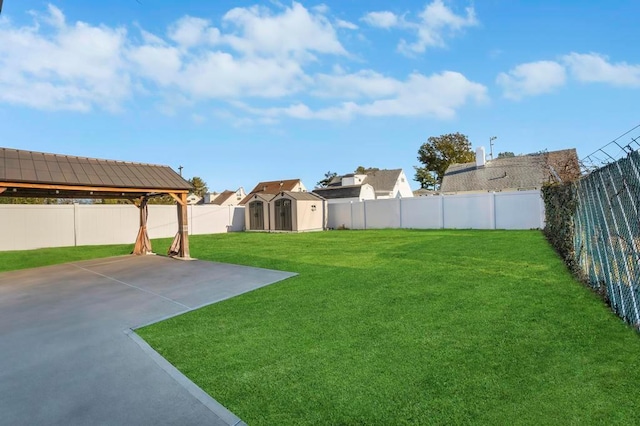 view of yard featuring a patio area, a shed, an outbuilding, and a fenced backyard