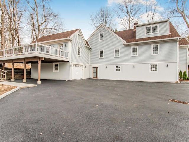 back of property with a deck and a garage