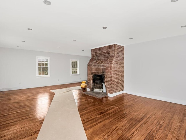 unfurnished living room featuring a brick fireplace and wood-type flooring